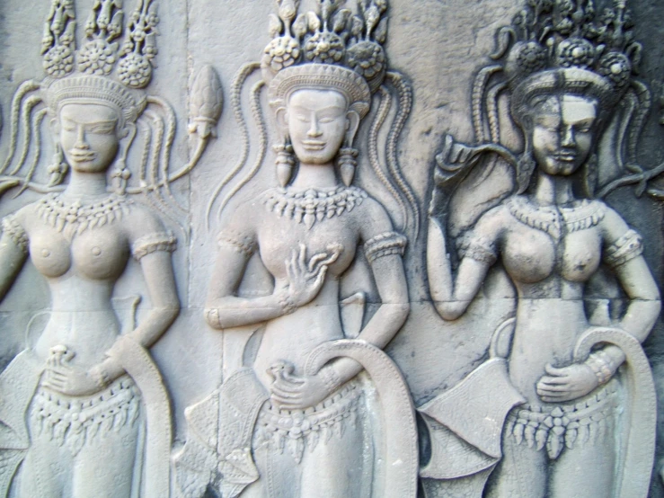 a large stone carving with two women holding a pot