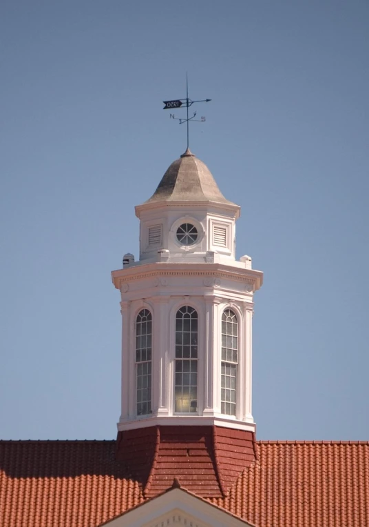 a tall building with a clock tower and weather vane