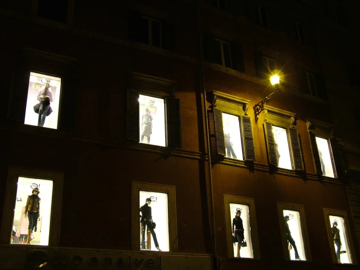 several people looking out windows on a building at night