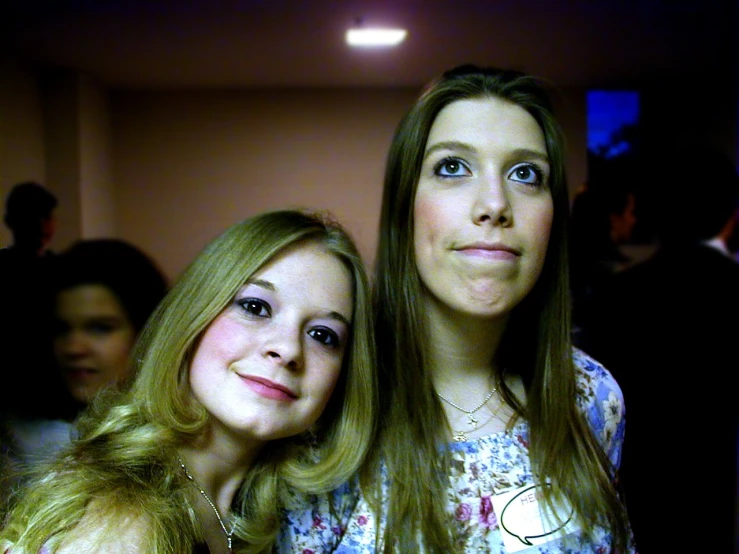 two girls stand in a room, posing for a pograph