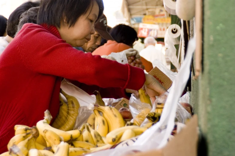 an asian woman is shopping for fruit at a market