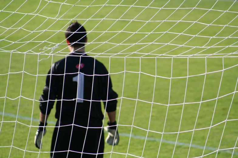 soccer goalie on the grass behind a net