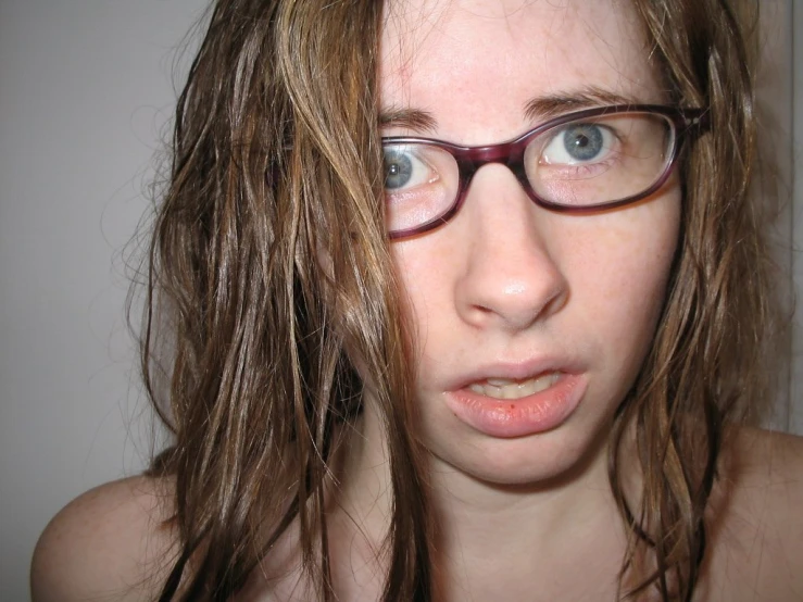 a girl with long hair and glasses making a face