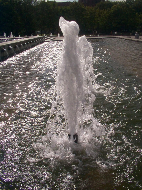 a water fountain shooting up water with the sun shining on it