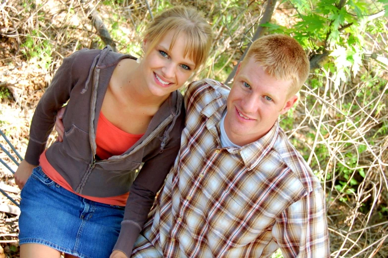 a couple posing for a portrait together in a wooded area