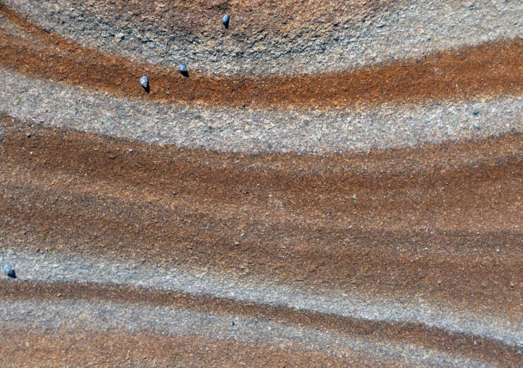 a rock and sand formation with tiny birds on it