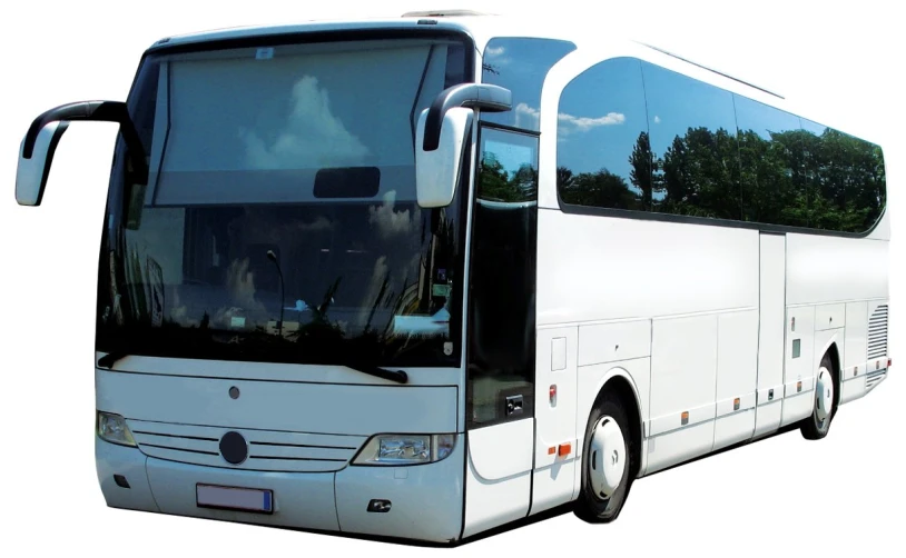 a white bus driving down the road near trees