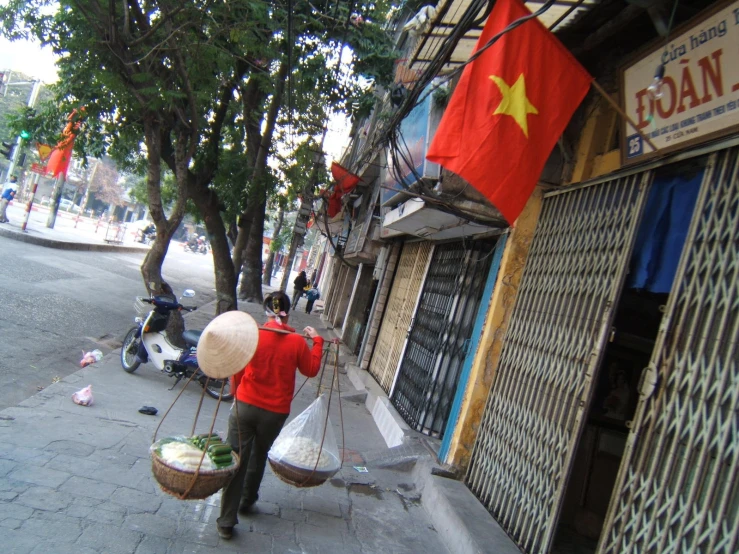 a street vendor walks down the street in a red shirt with an orange flag