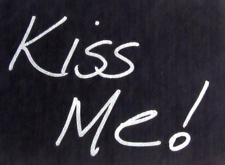 white writing on a blackboard reading kiss me