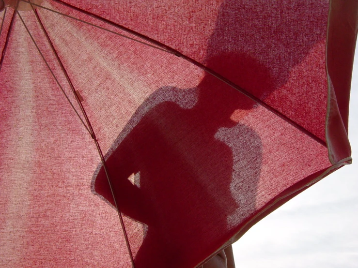 a shadow of a person under a red umbrella