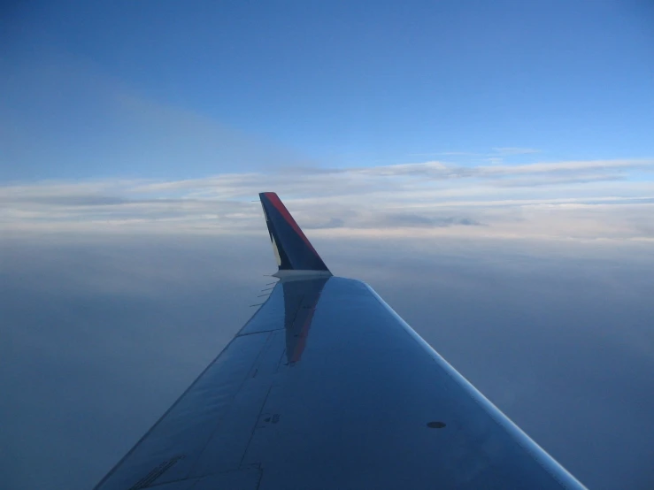 the wing of an airplane that is above clouds