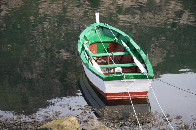 a boat docked in the water with rocks near it