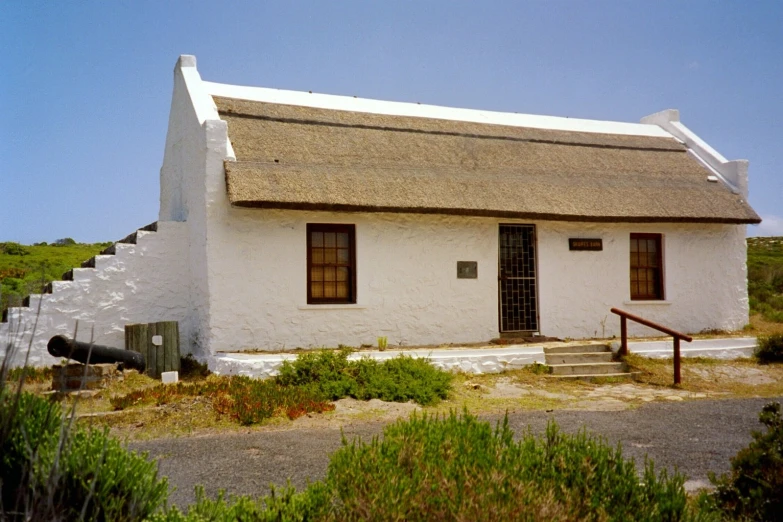 an old thatched roof building with a pipe running into the door