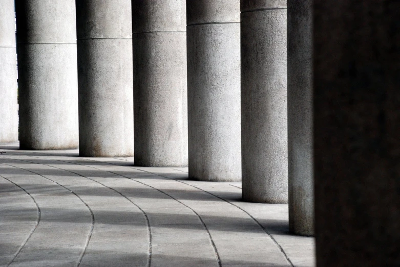 the man is sitting on a bench under many pillars