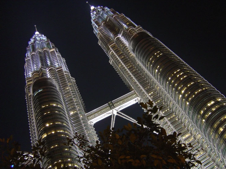 two towers lit up at night with lights on the sides