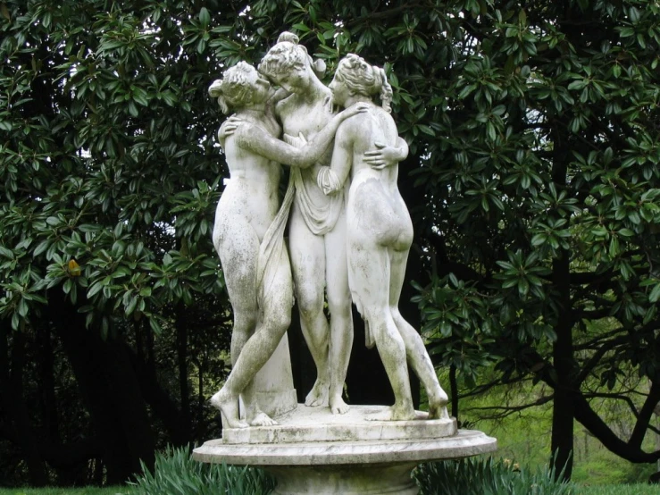 statue of two women emcing each other in a garden