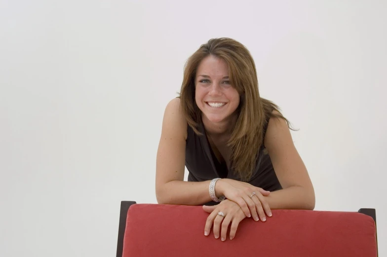 a woman in black shirt leaning on a red bench