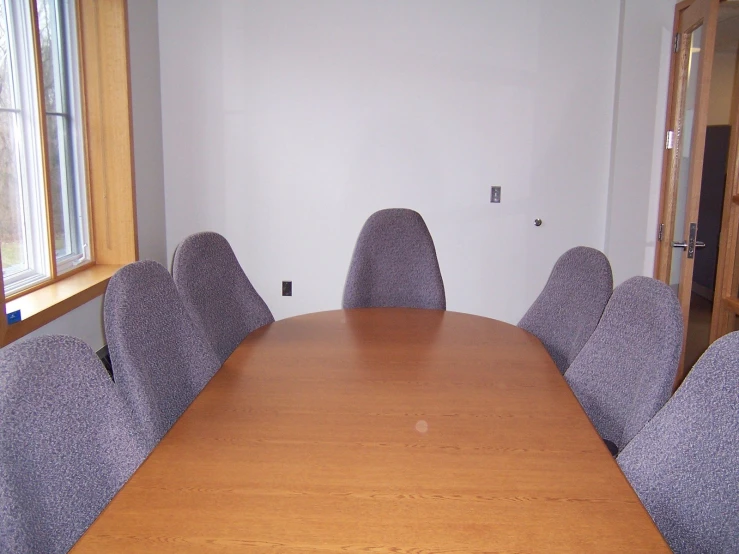 a room with a wooden table and gray chairs