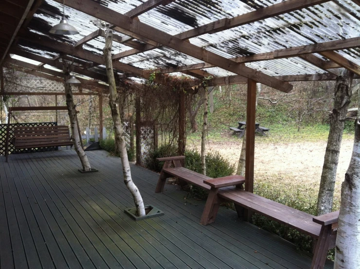 there is a bench under a wooden roof