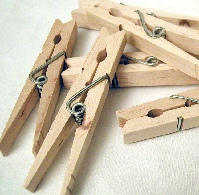 a pile of wooden clothes pins next to some nails