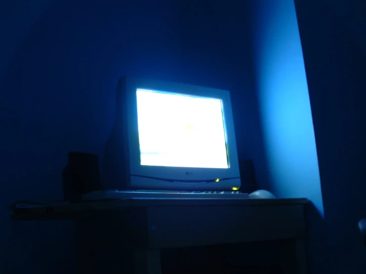 a desktop computer on top of a desk in a dark room