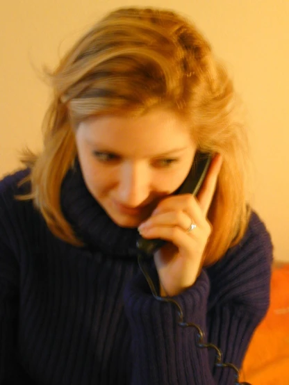 a woman in a blue sweater is talking on the phone