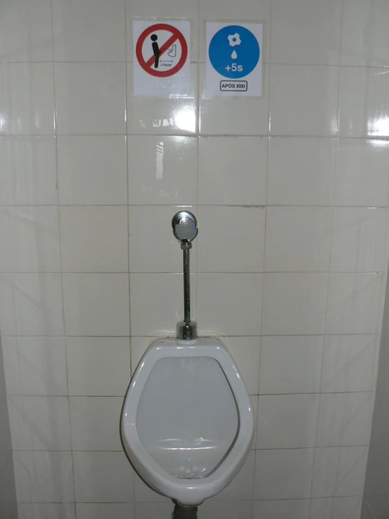 there is a no peeing sign on the wall and a white toilet seat