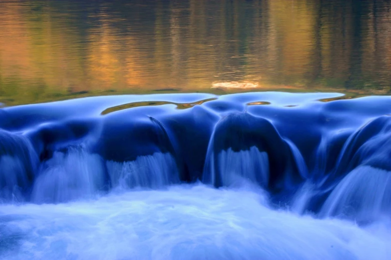 a small waterfall in a lake surrounded by trees