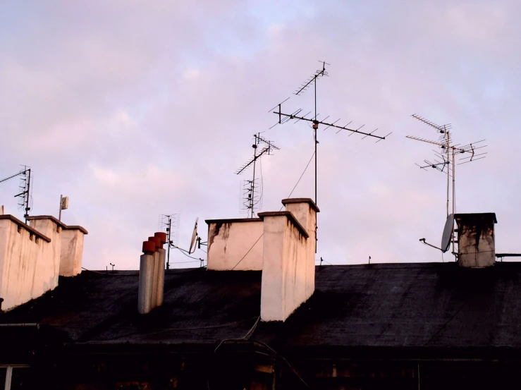 an overcast sky is pictured behind a building with three chimneys