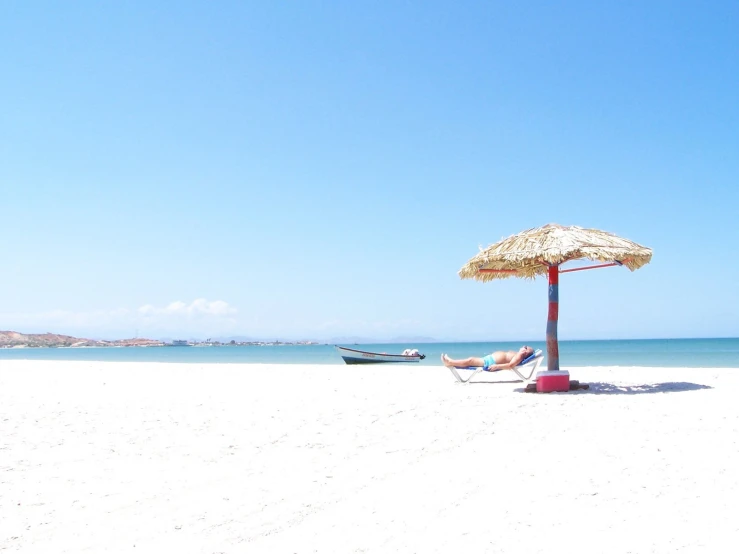 a beach with a umbrella and two boats near by