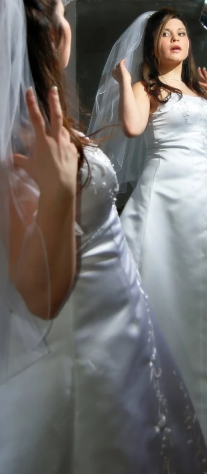 a bride wearing a white dress takes a picture of herself in the mirror