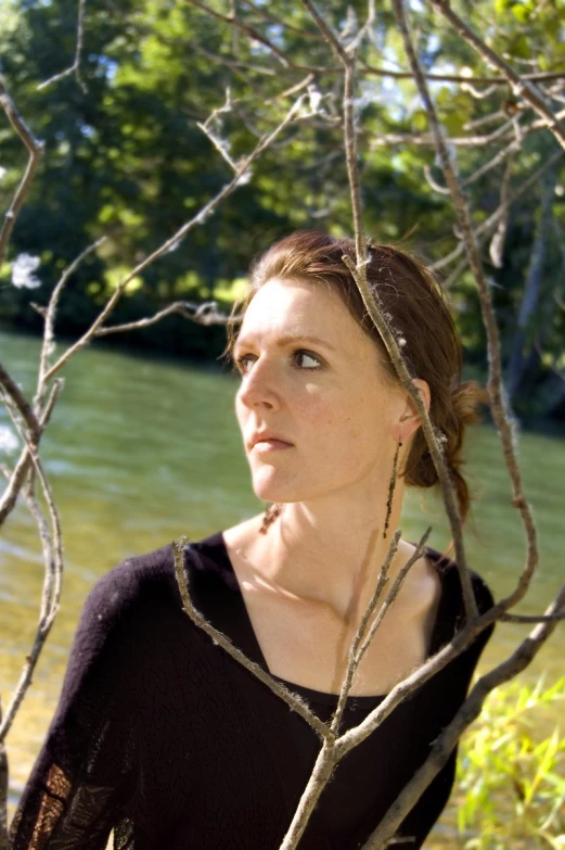 a young woman wearing a black shirt is posing in front of some water