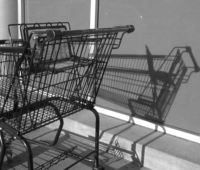 two empty shopping carts sit on a sidewalk