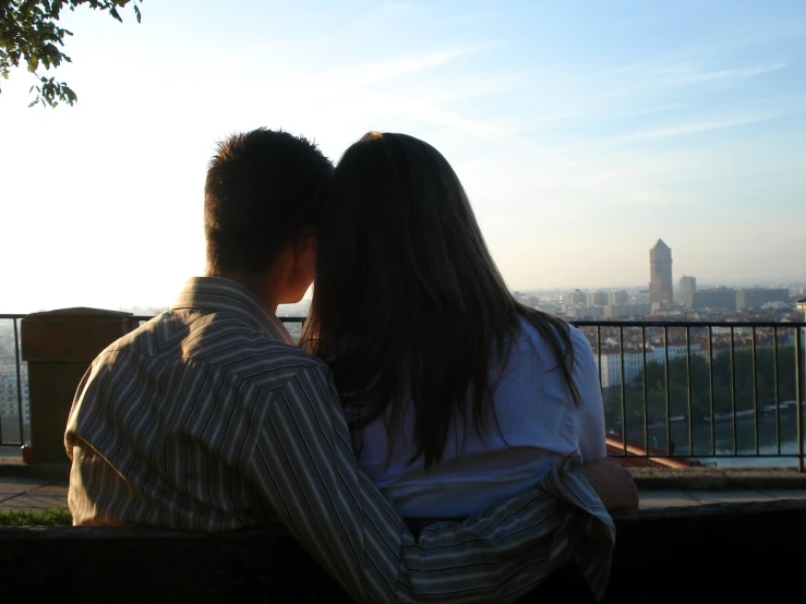 a young man and a woman sitting together as the sun sets