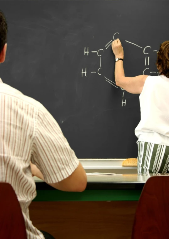 the man and woman are writing on the chalk board