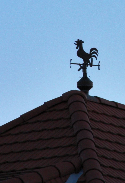 an old model rooster weathervane on top of a roof