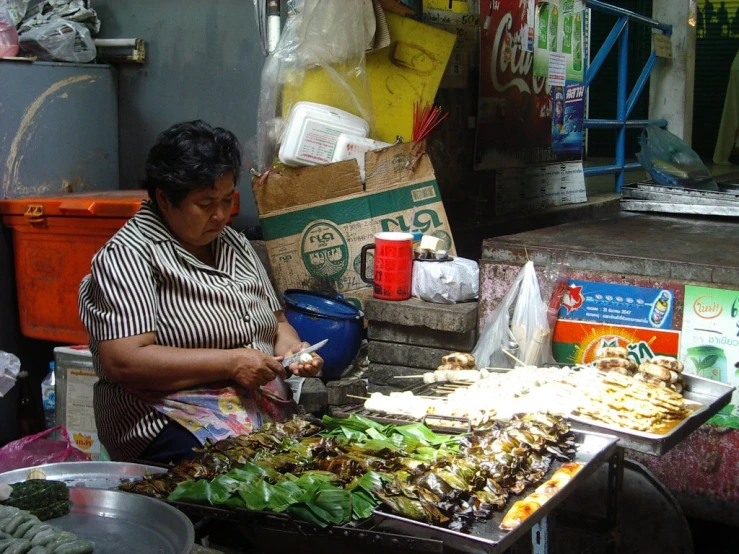 an older woman is cooking at a street vendor