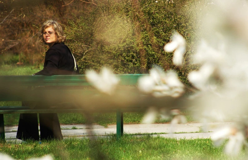 a woman sits on a bench and looks out over the field