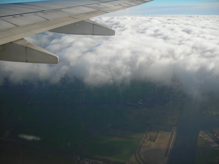 an airplane wing above a city below clouds