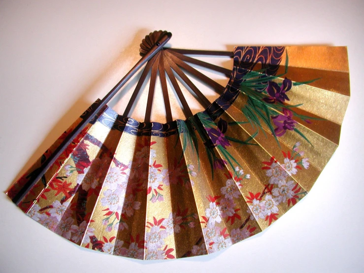 a gold paper fan hanging on a wall