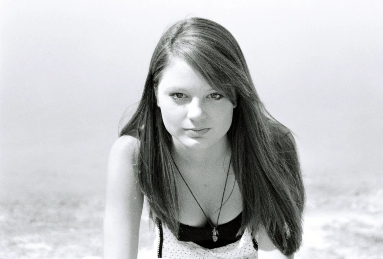 a girl sitting in the sand on top of a beach