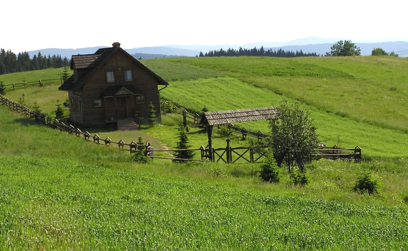 a house sitting on a green hill in the middle of nowhere