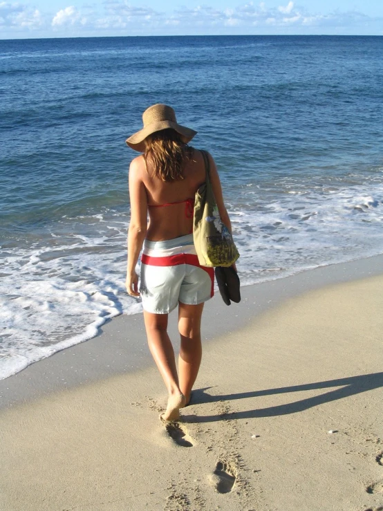 a person in white shorts walks on the beach