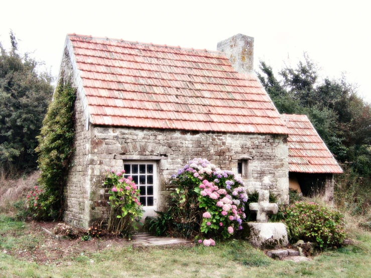 a small house is in the middle of flowers growing around it