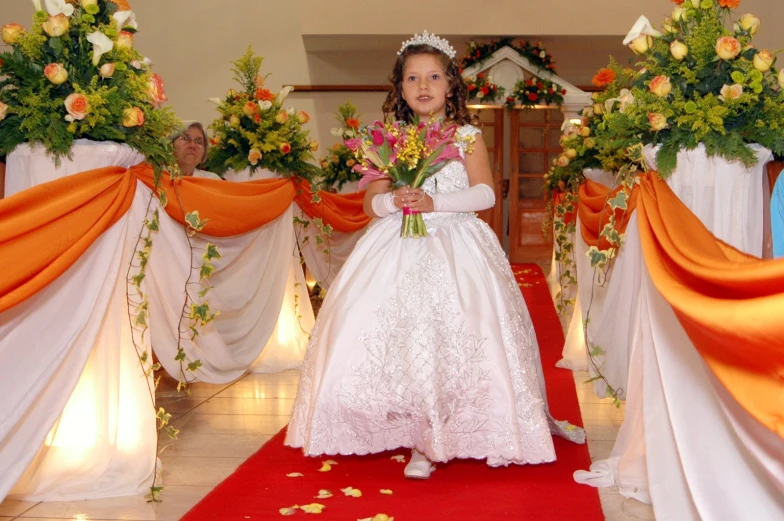 a  dressed in a white gown is standing in a church with flowers