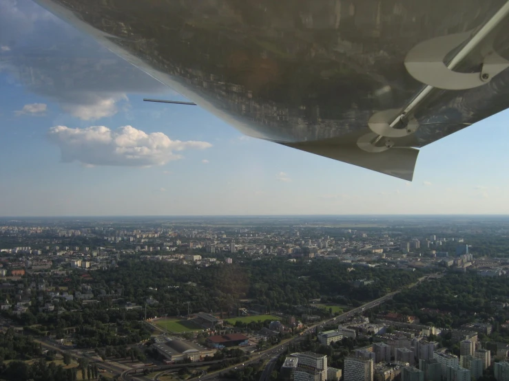 a plane wing flying over the top of some houses