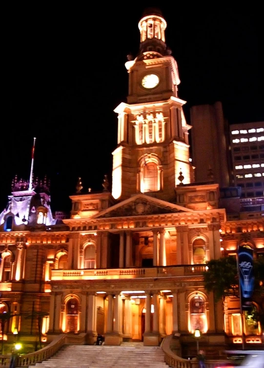 an old building at night with clock lit up