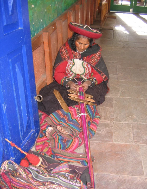 an indian woman sits on the ground near her colorful item