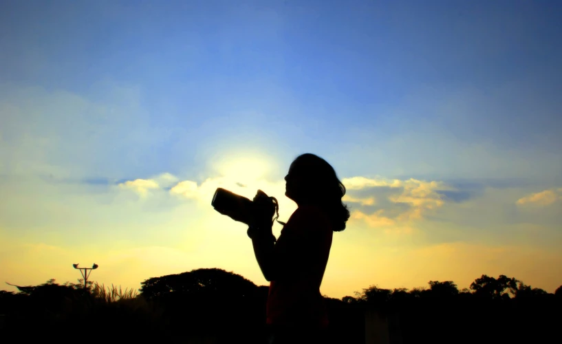 a person holding a cup next to the sun