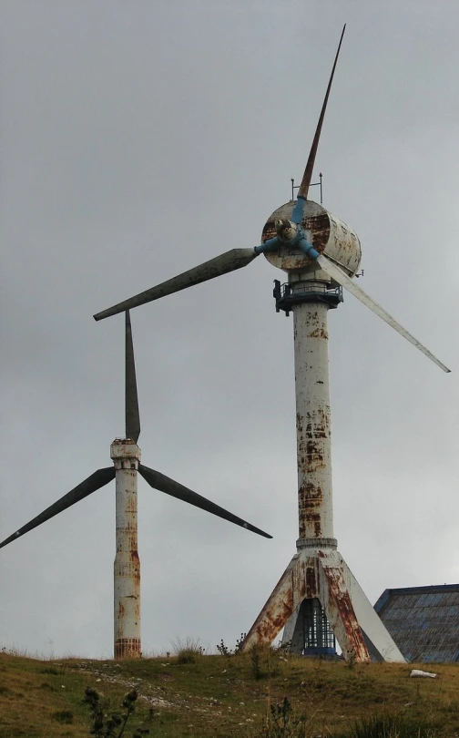 an old rusty pipe and wind turbine sits on a hill